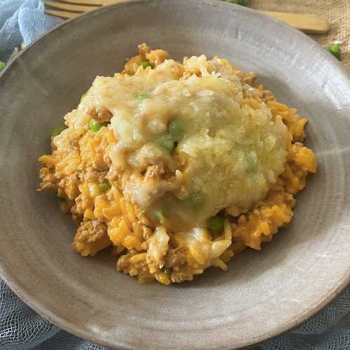 Yellow rice mixed with ground beef, onion and peas with melted cheese on top