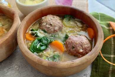 Clear soup filled with meatballs, carrot, spinach, celery and pasta noodles