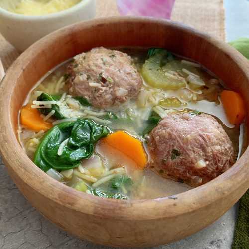 Clear soup filled with meatballs, carrot, spinach, celery and pasta noodles