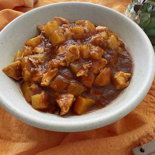 Chicken and pineapple cubes in sweet sauce in white bowl