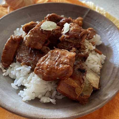 Pork cubes on jasmine rice with spices on top in brown bowl