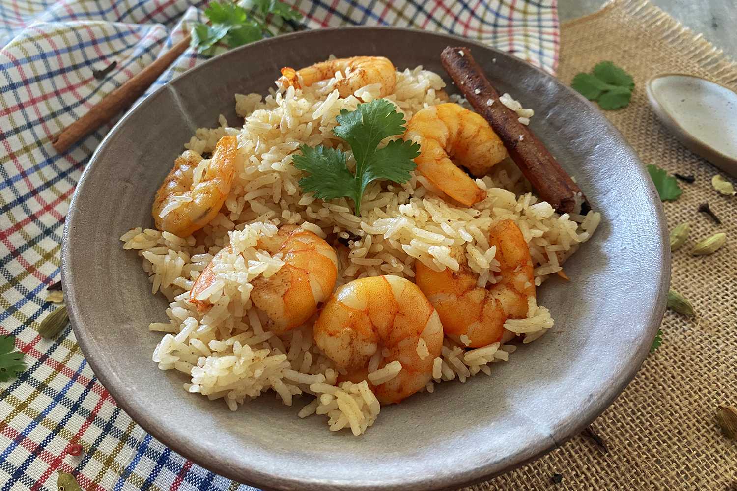 Jasmine rice with shrimp topped with parsley with cinnamon stick on side