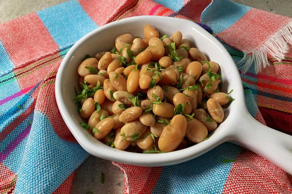 cooked white beans inside a white bowl top view