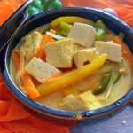 Tofu cubes mixed with yellow and green ball pepper strips in yellow curry sauce