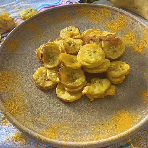 Banana chips slices on a gray plate with curcumin on sides