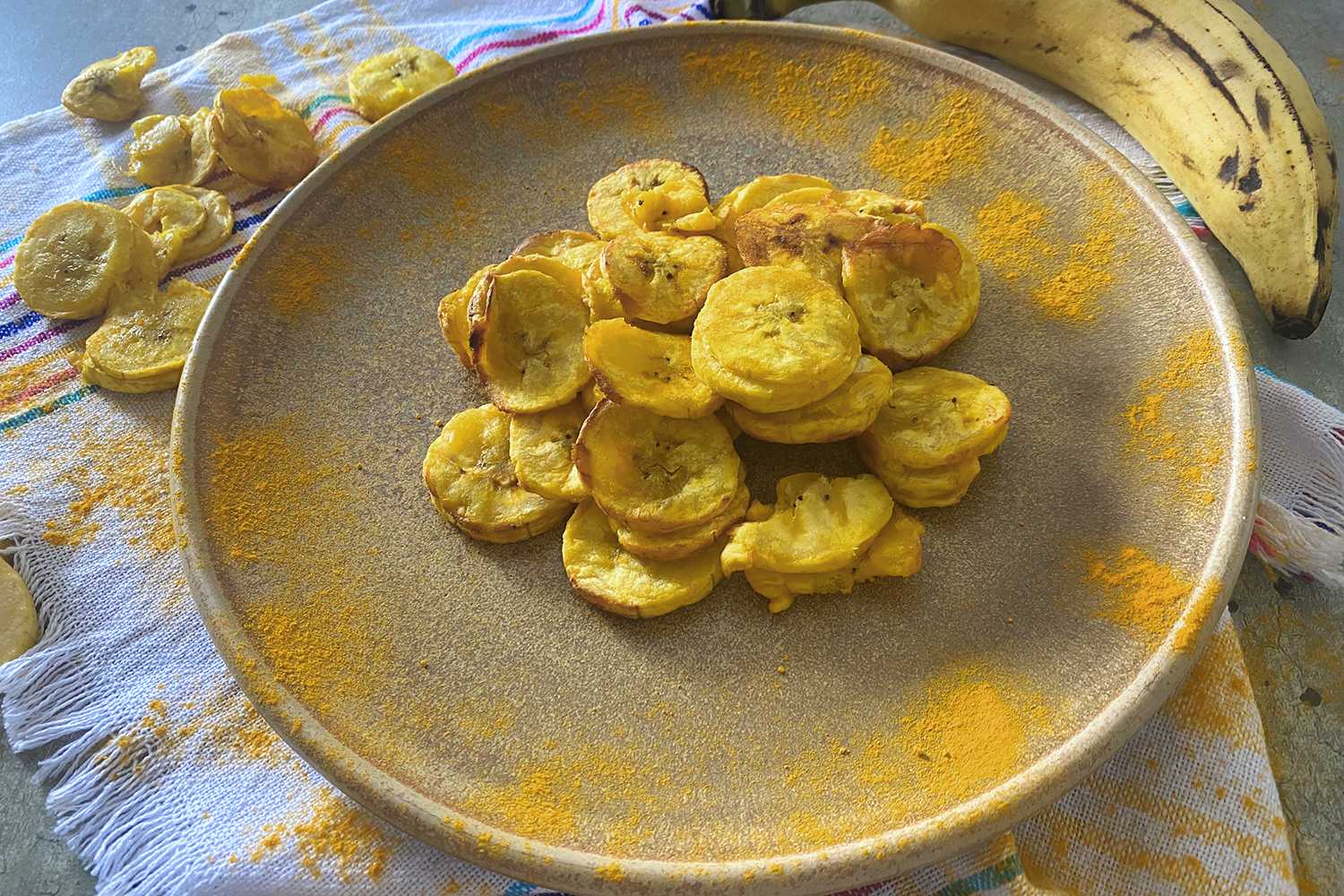 Banana chips slices on a gray plate with curcumin on sides
