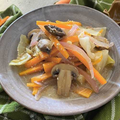 Clear soup with chopped cabbage, orange slices, red onion and slices mushrooms on top