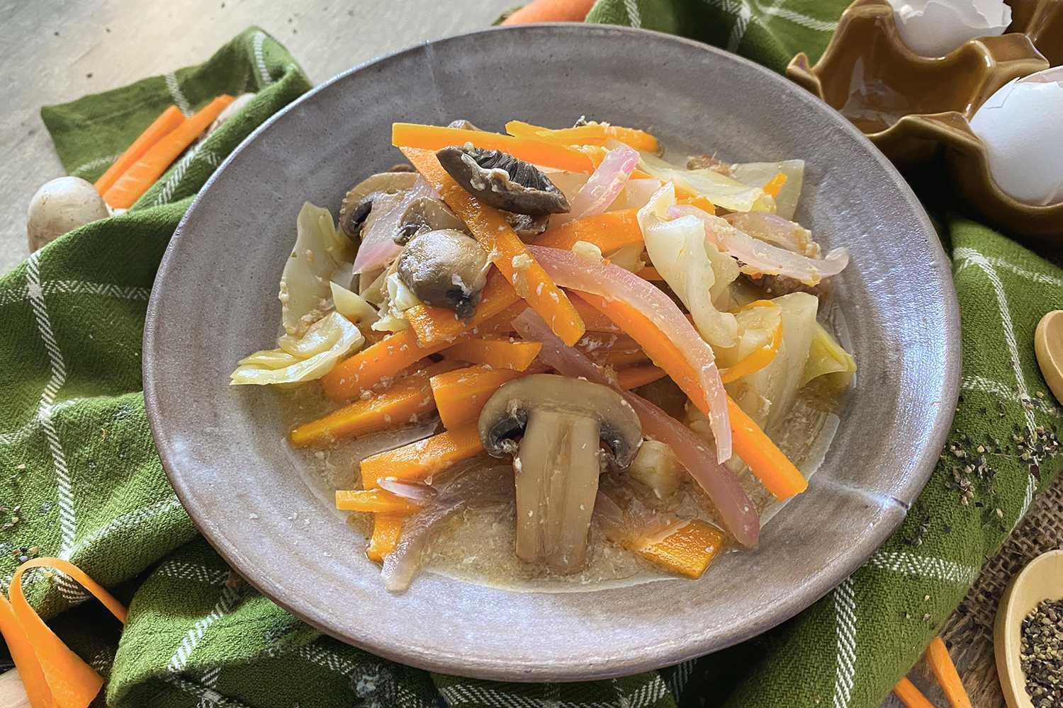 Clear soup with chopped cabbage, orange slices, red onion and slices mushrooms on top