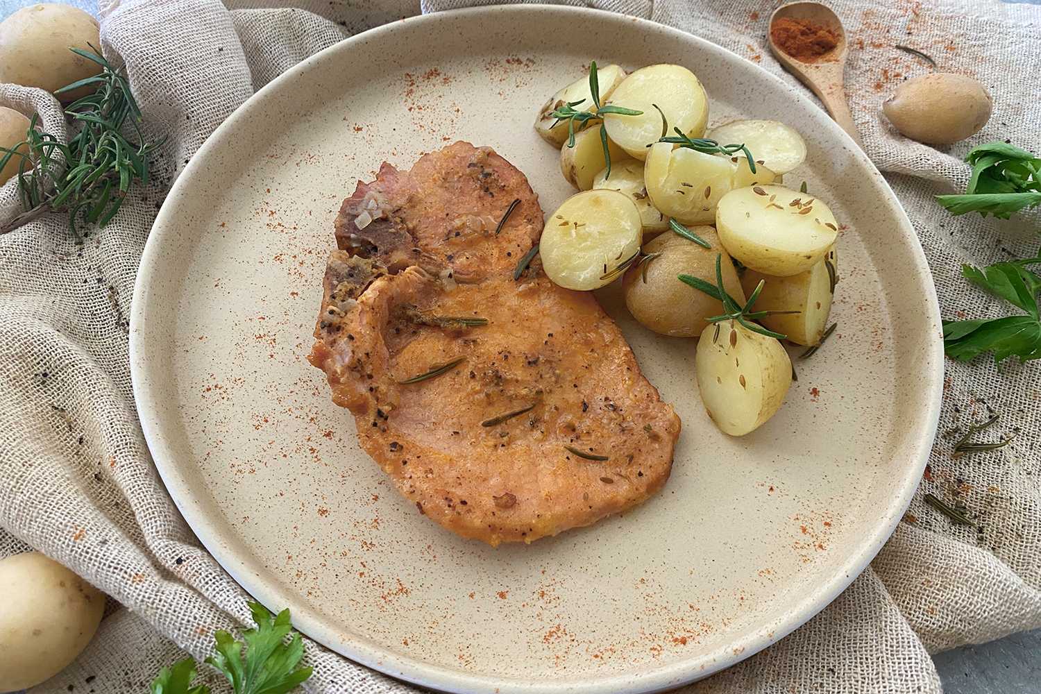 Pork Chop with roasted potatoes on side topped with rosemary and paprika 