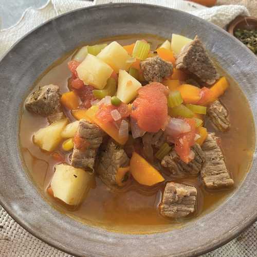 Beed cubes with potato cubes, chopped celery, carrot slices in a brown soup