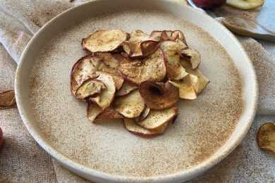 Red apple chips in white plate topped with cinnamon