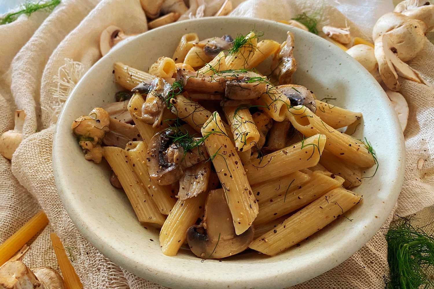 Penna pasta with chicken cubes and mushroom slices on a white bowl 