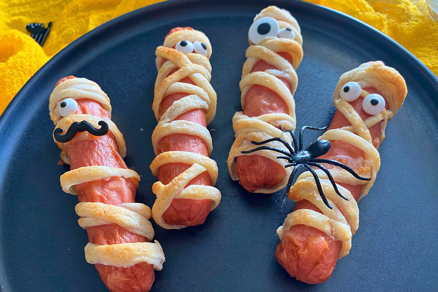 Hotdogs wrapped with cheese and dough strips with scary eyes and spider on top