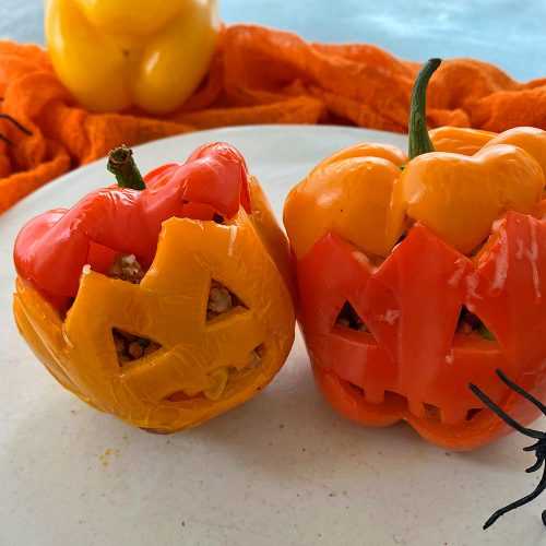 Red and orange bell peppers with scary eyes and mouth and plastic spider on side