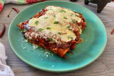 Five Enchiladas laying next to each other topped with bbq sauce and melted cheese with parsley