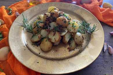 Roasted potatoes cut into half in brown plate topped with
