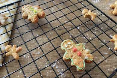 Gingerbread Cookies with green border and red buttons laying over a doted metal net