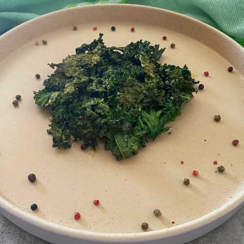 Kale chips in a white plate with Allspice around the plate