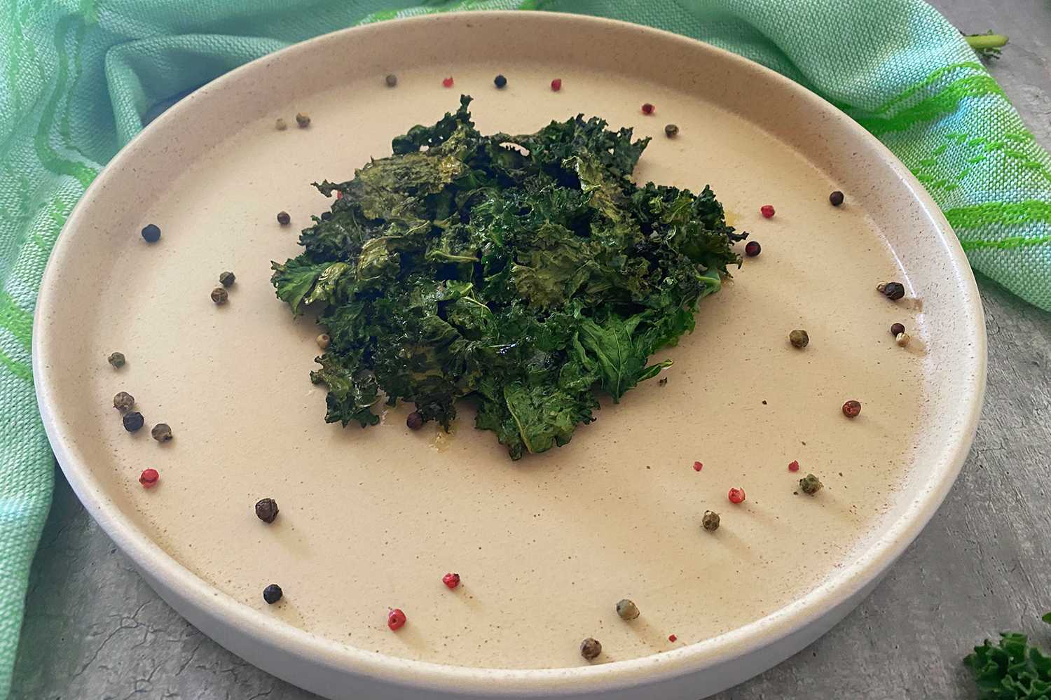 Kale chips in a white plate with Allspice around the plate