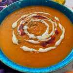 Blended orange soup topped with sour cream and spices