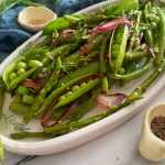green beans ready to be served with red onion slices in a white plate top view