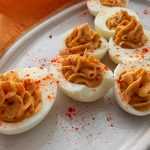 Hard boiled eggs cut into half filled with egg and mustard mixture and topped with paprika