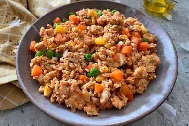 Ground turkey mixed with corn, carrot cubes and peas in a blue bowl