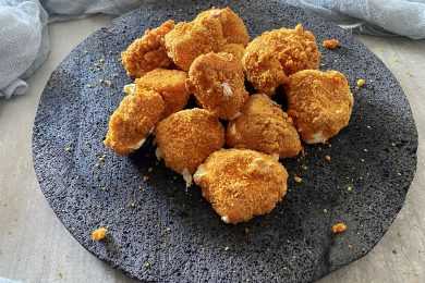 cheese curds coated with bread crumbs with melted cheese on a gray plate
