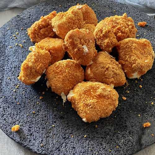 cheese curds coated with bread crumbs with melted cheese on a gray plate