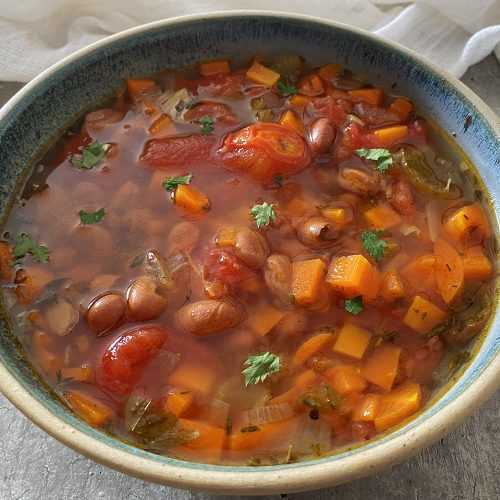Red soup with carrot cubes, beans and celery in tomato sauce