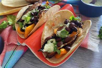 Two tacos filled with roasted mushrooms, black beans, bell peppers and parsley