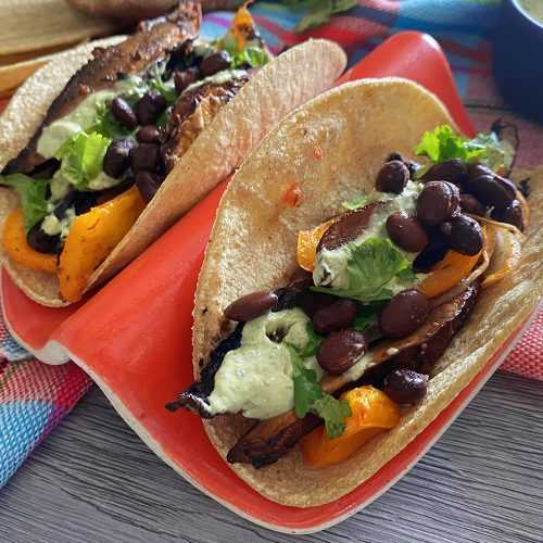 Two tacos filled with roasted mushrooms, black beans, bell peppers and parsley