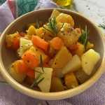 Yellow bowl filled with carrot, potato and pumpkin cubes topped with rosemary spring