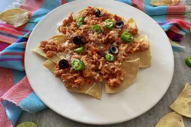 Nachos with ground beef with sauce topped with black ollives and chopped green chili