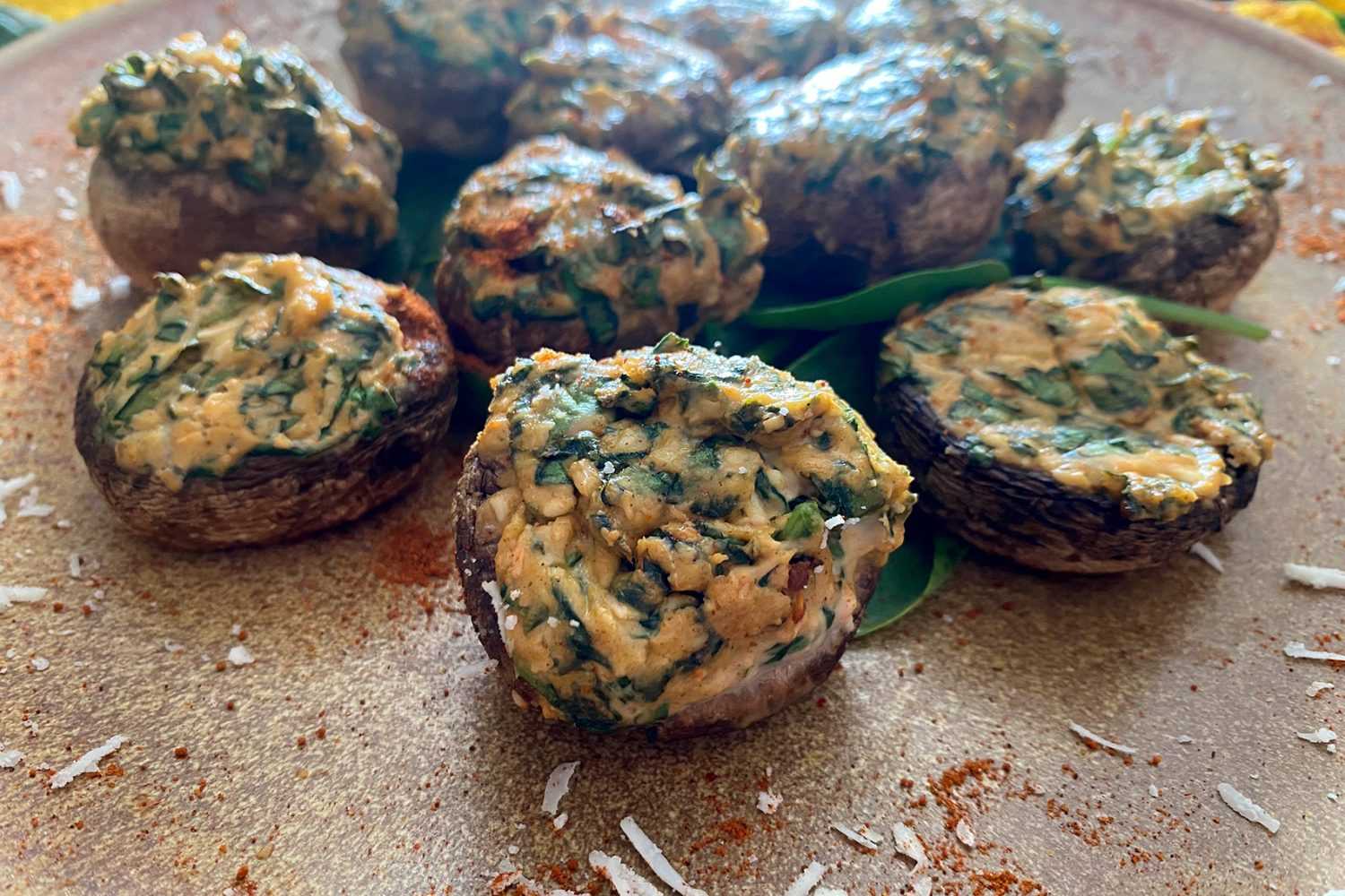 Roasted mushrooms filled with cheese and chopped spinach mixture on brown plate