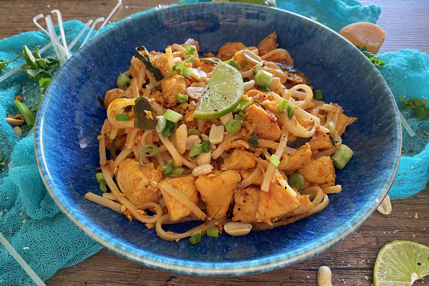 Rice noodles with chicken cubes topped with scallion, peanuts and a slice of lime