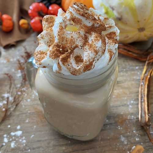 Pumpkin Spice Latte in a jar topped with whipped cream and cinnamon on a wooden table
