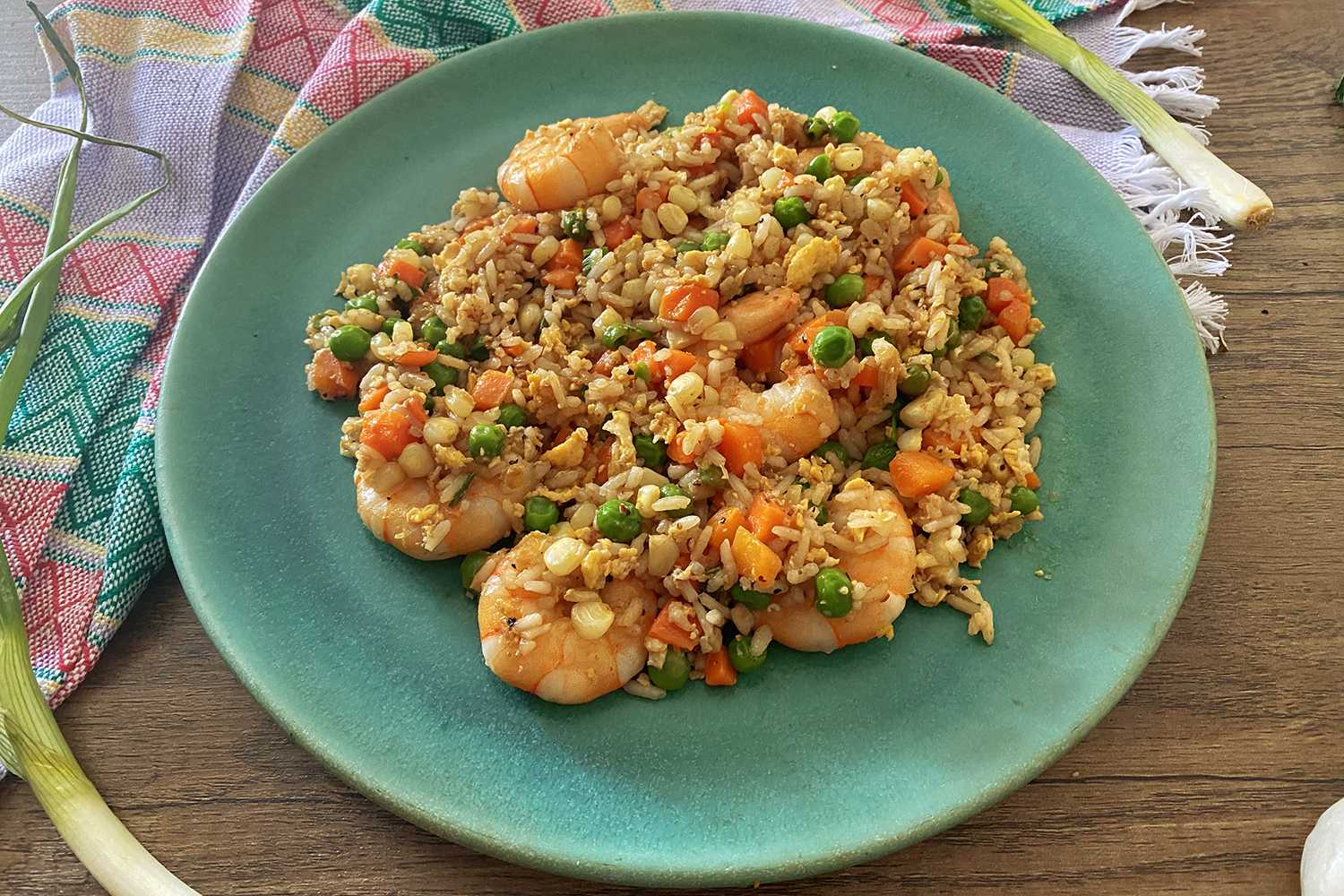 fried rice mixed with shrimp, peas and carrot cubes in a blue plate top view