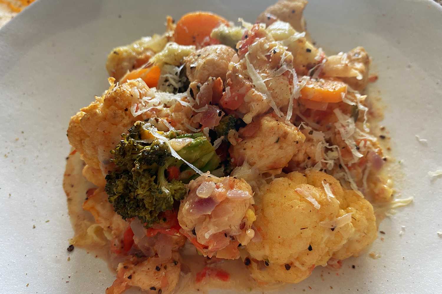 chicken cubes with broccoli florets, cauliflower and carrot cubes topped with melted cheese