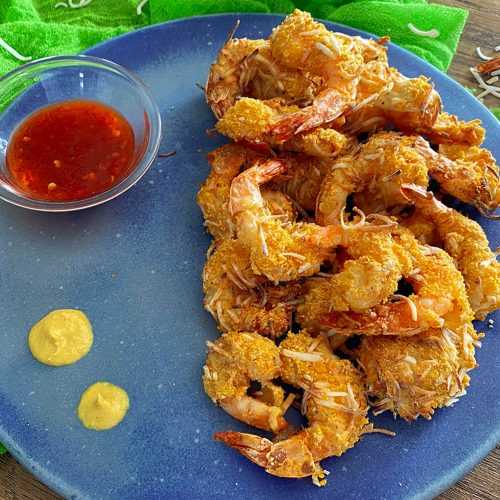 Fried shrimp coated with coconut on a blue plate with chili sauce on side