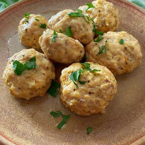 Homemade turkey meatballs topped with chopped parsley on a brown plate