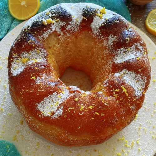 lemon bundt cake with sugar powder and lemon zest on top and lemon slices on side