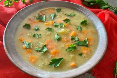 Lentil soup topped with carrot cubes and chopped parsley
