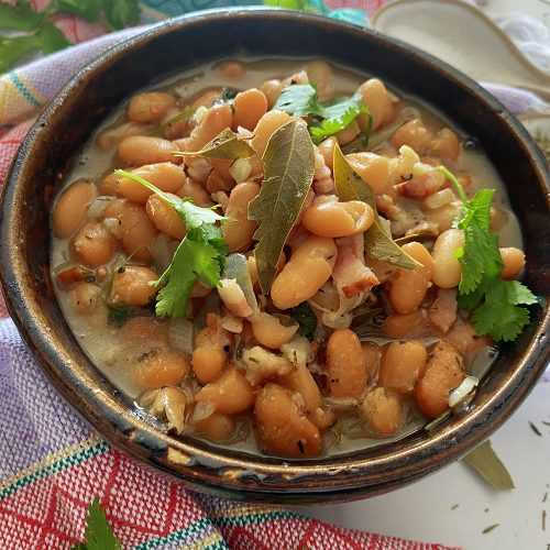 charro beans in a soup top with bay leaves in a brown bowl