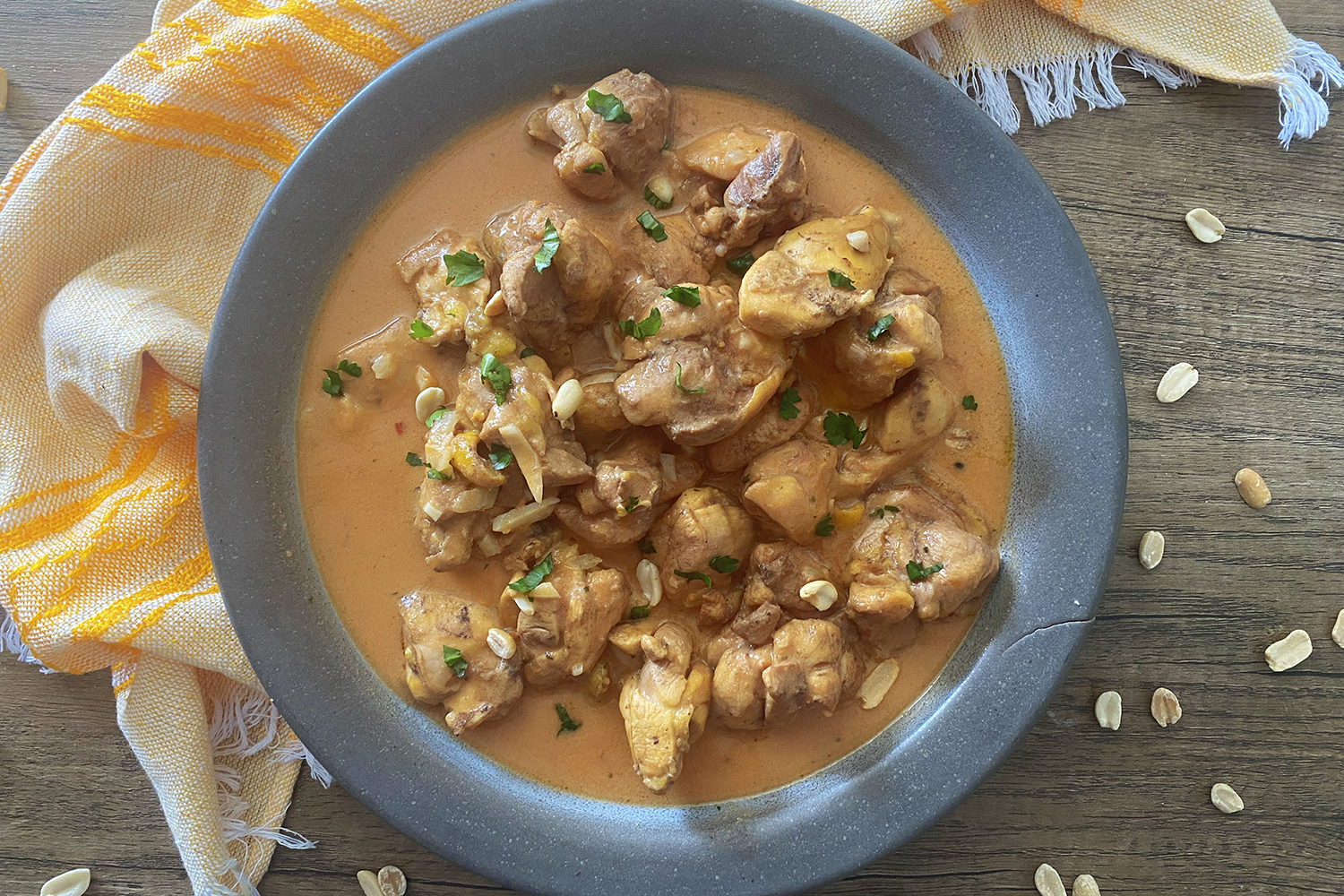 Peanut Butter Chicken pieces in an orange sauce in a blue plate top view