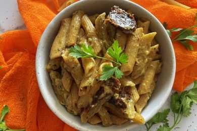 penne pasta with peso sauce and parsley leaf on top in a gray bowl