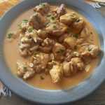 chicken cubes in peanut butter sauce top with parsley in a grey plate