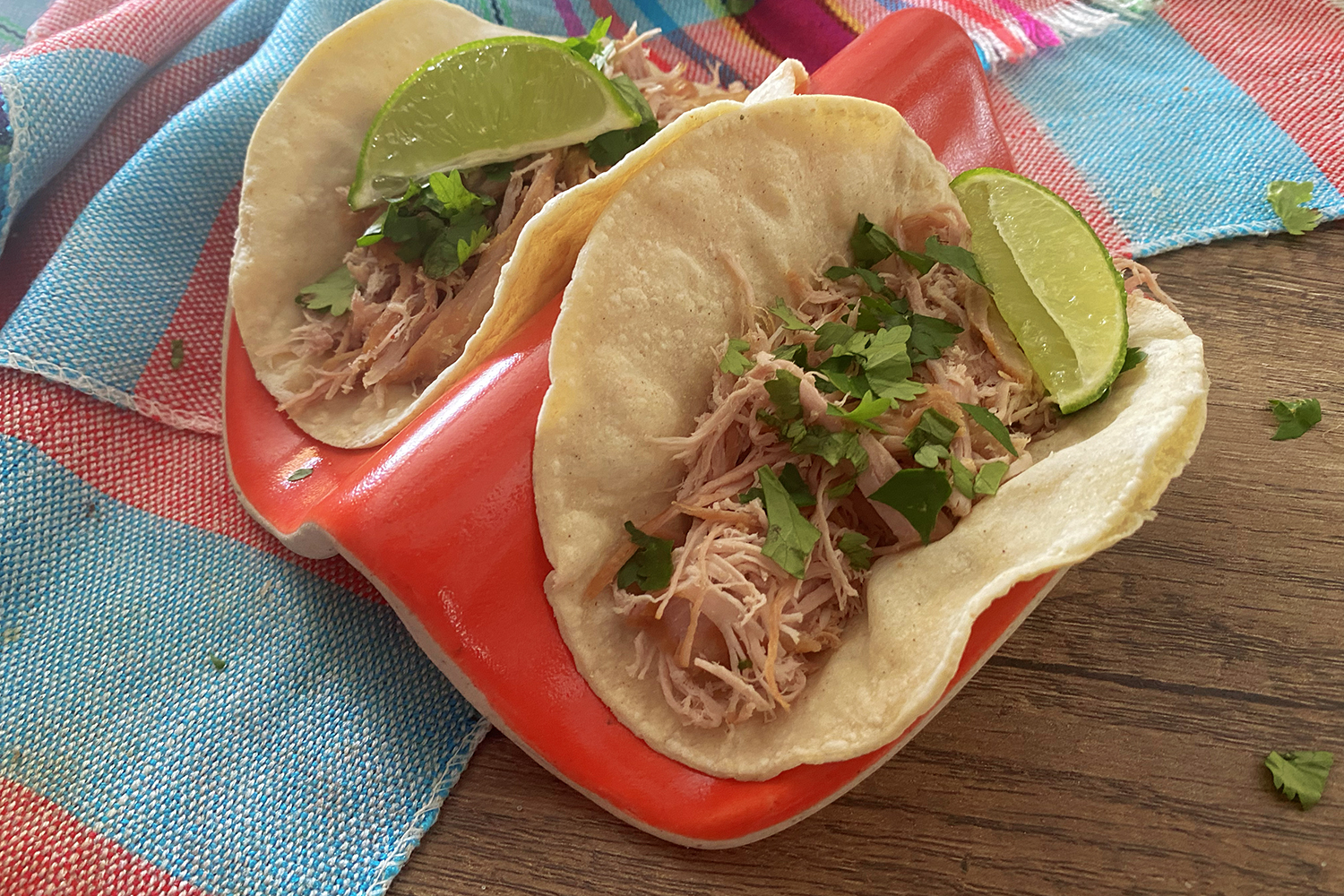red plate with two tacos on it and limes