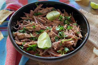 black bowl full of shredded beef topped with lime
