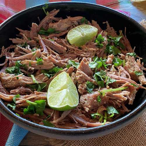 black bowl full of shredded beef topped with lime